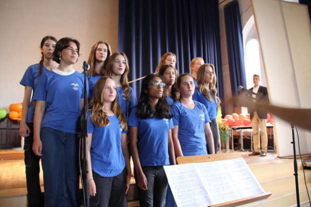 elf Schülerinnen in blauen T-Shirts mit dem weißen Logo des Lilienthal-Gymnasiums (stilisirter Vogel) auf einer Bühne